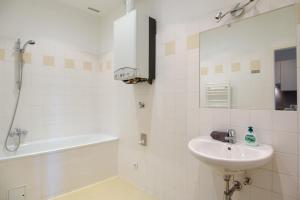biała łazienka z umywalką i wanną w obiekcie Central Living Apartment 1090 Vienna w Wiedniu