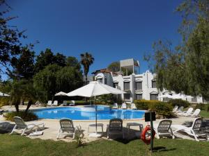 a pool with chairs and an umbrella and a building at Hotel Palmar in Colón