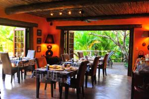 un comedor con mesas y sillas en una habitación con puerta abierta en Kwalucia Private Safari Retreat, en St Lucia