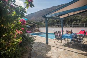 a patio with a table and chairs next to a pool at Villa Afou in Afráta