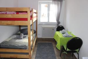 Winhöring的住宿－ZV-Scholtz Gästehaus Eisenfelden，一间卧室配有一张双层床和一张带绿桌布的桌子。