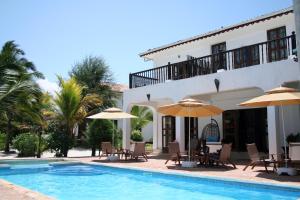 a villa with a swimming pool and chairs and umbrellas at Moonshine Uroa Boutique Hotel in Uroa