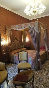 a bedroom with a bed and two chairs and a chandelier at Casa Pisani Canal in Venice