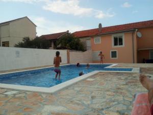 a group of people playing in a swimming pool at Nevera Apartments Pašman,Banj in Banj