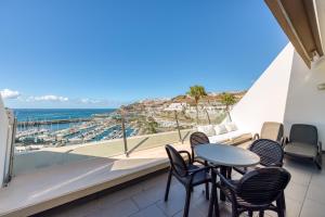 a balcony with chairs and a table and a view of the ocean at Holiday Club Puerto Calma in Puerto Rico de Gran Canaria
