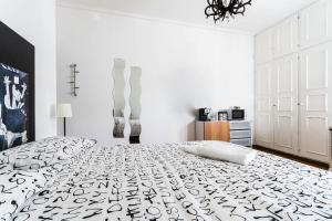 a white bedroom with a bed with a black and white bedspread at B&B Viale Dei Colli Portuensi 589 in Rome
