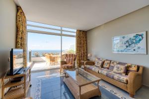 a living room with a couch and a table and a tv at Holiday Club Jardin Amadores in Amadores