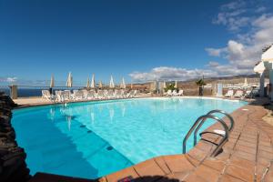 a large swimming pool with chairs and the ocean at Holiday Club Jardin Amadores in Amadores