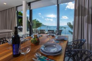 a wooden table with wine glasses and a view of the ocean at Villa Puntin - Drvenik in Drvenik