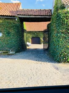an ivy covered gate to a building with a garage at La Ferme des Roses in Tournai