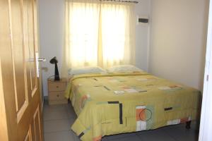 a bedroom with a bed with a yellow blanket at Rachel's Apartments in Paramaribo
