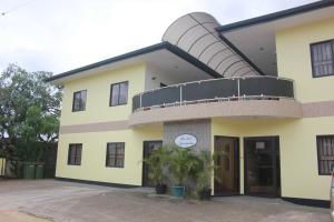 a large yellow building with a balcony on top at Rachel's Apartments in Paramaribo