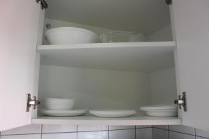 a cabinet filled with white bowls and plates at Rachel's Apartments in Paramaribo