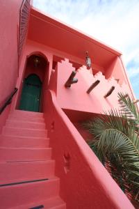 un edificio rosa con escaleras que conducen a una puerta en A Fei Surf Inn III, en Nanwan