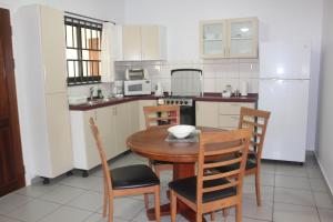 a small kitchen with a wooden table and chairs at Rachel's Apartments in Paramaribo