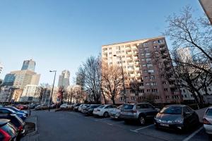 parking z samochodami zaparkowanymi przed wysokim budynkiem w obiekcie Noctis Apartment Pańska III w Warszawie