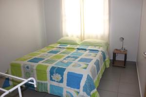 a bedroom with a bed with a quilt on it at Rachel's Apartments in Paramaribo