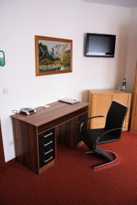 a desk with a chair and a computer on it at Heidekönig Hotel Celle in Celle