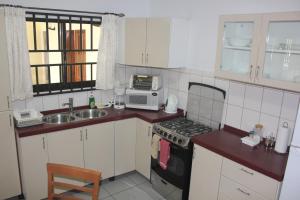 a kitchen with a sink and a stove and a microwave at Rachel's Apartments in Paramaribo