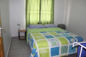 a bedroom with a bed with a green curtain at Rachel's Apartments in Paramaribo
