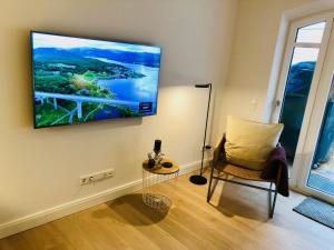 a living room with a chair and a tv on the wall at Ankerplatz-Sylt @Haus Mateika in Westerland (Sylt)