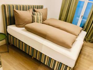 a couch with pillows on it with a window at Ankerplatz-Sylt @Haus Mateika in Westerland (Sylt)