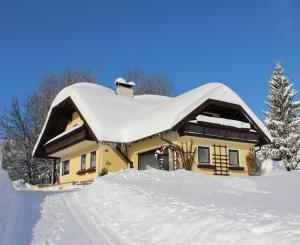 a house covered in snow with a pile of snow at Ferienwohnung Claudia in Faistenau