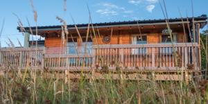 a wooden house with a fence in front of it at Enlli Fach cabin sleep's 2 adults and 2 children 2 dogs welcome not suitable for contract workers due to parking height restrictions in Borth