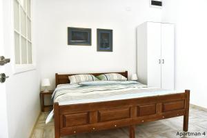 Vajda Apartments في نوفي ساد: غرفة نوم بسرير خشبي في غرفة بجدران بيضاء