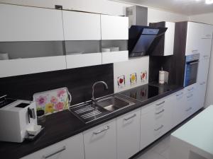 una cocina con armarios blancos y fregadero en Atempause, en Nideggen