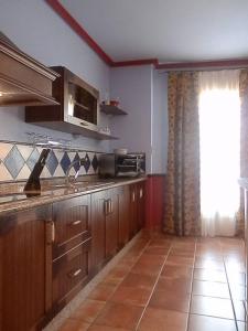 kuchnia z drewnianymi szafkami i dużym oknem w obiekcie -2-COMO EN CASA, en centro historico de Ubeda w mieście Úbeda