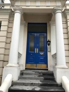 ロンドンにあるStylish Notting Hill Gate Flatの階段付きの白い建物の青い扉