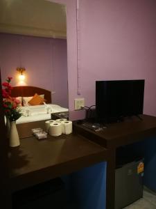 a room with a desk with a television and a bed at Weixiao Lanta Resort in Ko Lanta