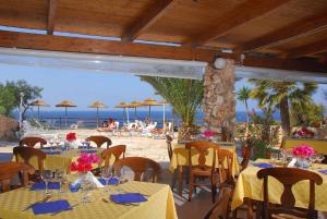 a restaurant on the beach with tables and chairs at Villaggio La Roccia camping in Lampedusa