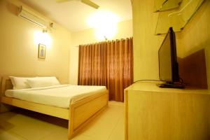a bedroom with a bed and a flat screen tv at Falcon Suites Residency Road in Bangalore