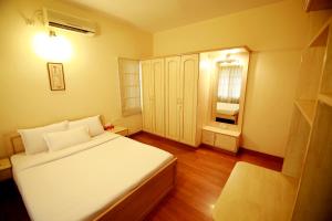 ein kleines Schlafzimmer mit einem weißen Bett und einem Fenster in der Unterkunft Falcon Suites Residency Road in Bangalore