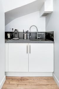 a kitchen with white cabinets and a sink at Freedomus Marne-La-Vallée "Côté Loft" in Esbly