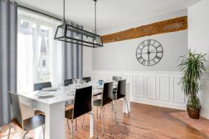 a dining room with a white table and black chairs at Freedomus Marne-La-Vallée "Le Briard" in Esbly