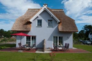 una casa con tetto di paglia e sedie di Haus Steuerbord a Zirchow