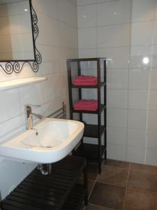 Un baño con lavabo y estante con toallas. en Mooi zo 2, en De Koog