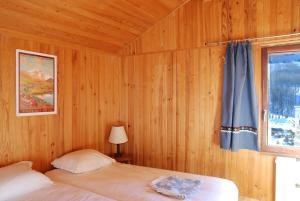 1 dormitorio con 1 cama con cortina azul y ventana en grand chalet plein sud en Montgenèvre