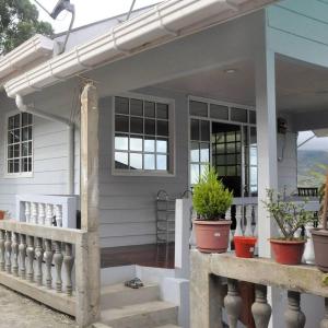 a white house with potted plants on the porch at Azrien Homestay Kundasang in Kundasang
