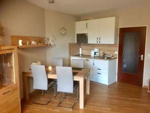 - une cuisine avec une table en bois et des chaises blanches dans l'établissement Lord Nelson Apartment 13, à Cuxhaven