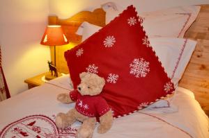 ein Teddybär auf einem Bett mit einem roten Kissen in der Unterkunft ECRINS ETOILE C9 in Samoëns