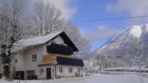 een huis bedekt met sneeuw met een berg op de achtergrond bij Haus-am-Sonnenweg in Lackenhof
