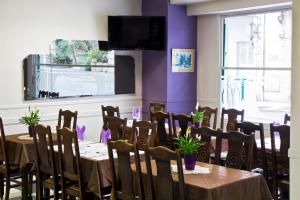 a dining room with tables and chairs and a purple wall at Hôtel Croix des Nordistes in Lourdes