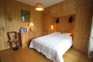 a bedroom with a white bed and a chair at Orée des pistes in Combloux
