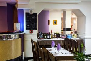 a dining room with tables and chairs and purple walls at Hôtel Croix des Nordistes in Lourdes