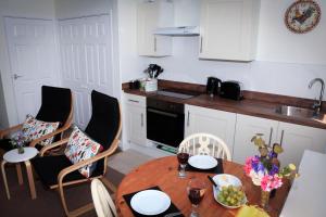 uma cozinha com uma mesa de madeira com cadeiras e um lavatório em Lowerbourne House Studio em Porlock