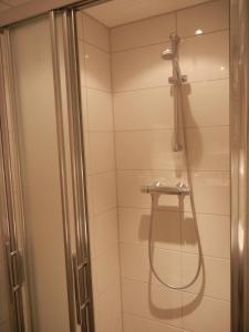una ducha con puerta de cristal en un baño en Mooi zo 2, en De Koog